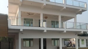 Ein modernes, zweistöckiges Gebäude mit flachem Dach, großen Fenstern und einer überdachten Außenbereich mit einer Treppe, die zu der oberen Etage führt.