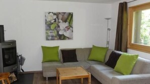 Een woonkamer met een bank, een houten salontafel en een schilderij aan de muur.