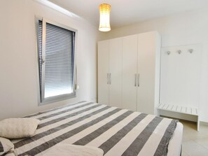 Ein Schlafzimmer mit einem Bett, einem Kleiderschrank und einem Fenster mit Jalousien.