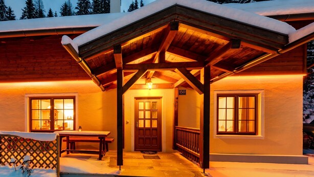 Eine Holzhütte mit überdachter Veranda, einer Bank und einer Tür mit der Nummer 150.