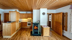 Ein Holzinnenraum mit einem zentralen Kamin, Holzschränken und einer gefliesten Rückwand.