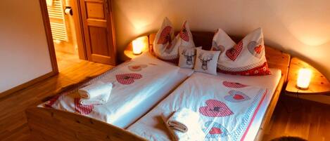 A double bed with a checkered bedspread and matching pillows, a wooden headboard, and bedside lamps.