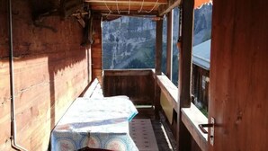 A wooden cabin with a small dining area featuring a table and benches, a view of a mountainous landscape through large windows. - Husmättli by Interhome (Lauterbrunnen)