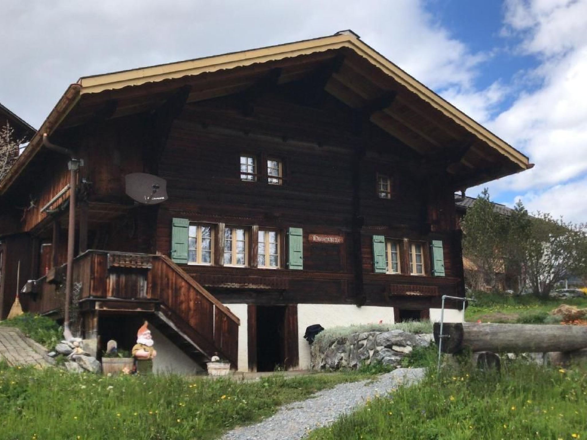 Un chalet en bois doté d’un toit à forte pente, d’un balcon et d’un chemin de pierre menant à l’entrée.