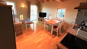 A cozy living room with a wooden ceiling, a dining area with a table and chairs, a kitchen with a stove, and a TV in the background. - Villa Albatros in Oberdellach by Interhome (Oberdellach)