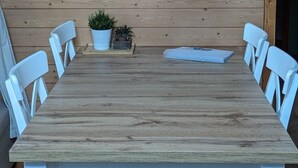 A wooden dining table with white chairs, a hanging light fixture, and a small potted plant on the table. - Margrit Ost by Interhome (Lauterbrunnen)