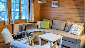 A cozy cabin interior with a sofa, two armchairs, a small table, and a hanging lamp. - Margrit Ost by Interhome (Lauterbrunnen)