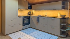 A compact kitchen with a skylight, built-in appliances, and a tiled floor. - Margrit Ost by Interhome (Lauterbrunnen)