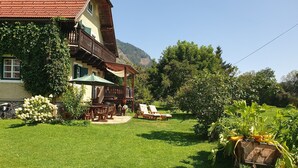 En traditionel chalet med en træbalkon, en terrasse med udendørs møbler og en velholdt have.