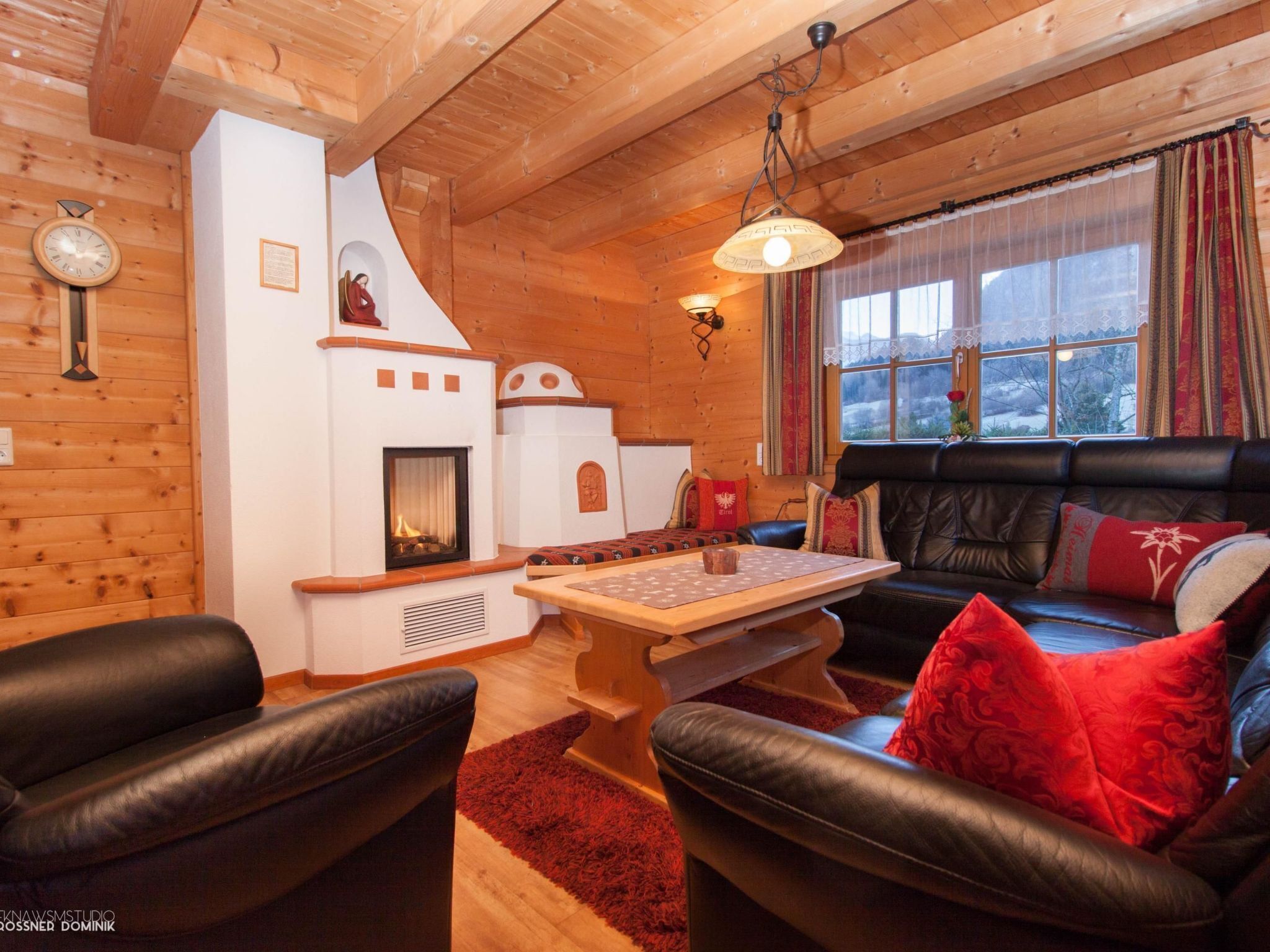 A cozy cabin interior with a fireplace, leather seating, and a wooden ceiling.