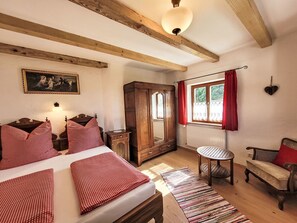 A bedroom with a bed, a wooden wardrobe, a chair, a small table, and a window with curtains. - in Sankt Koloman mit Bergblick by Interhome (St. Koloman)