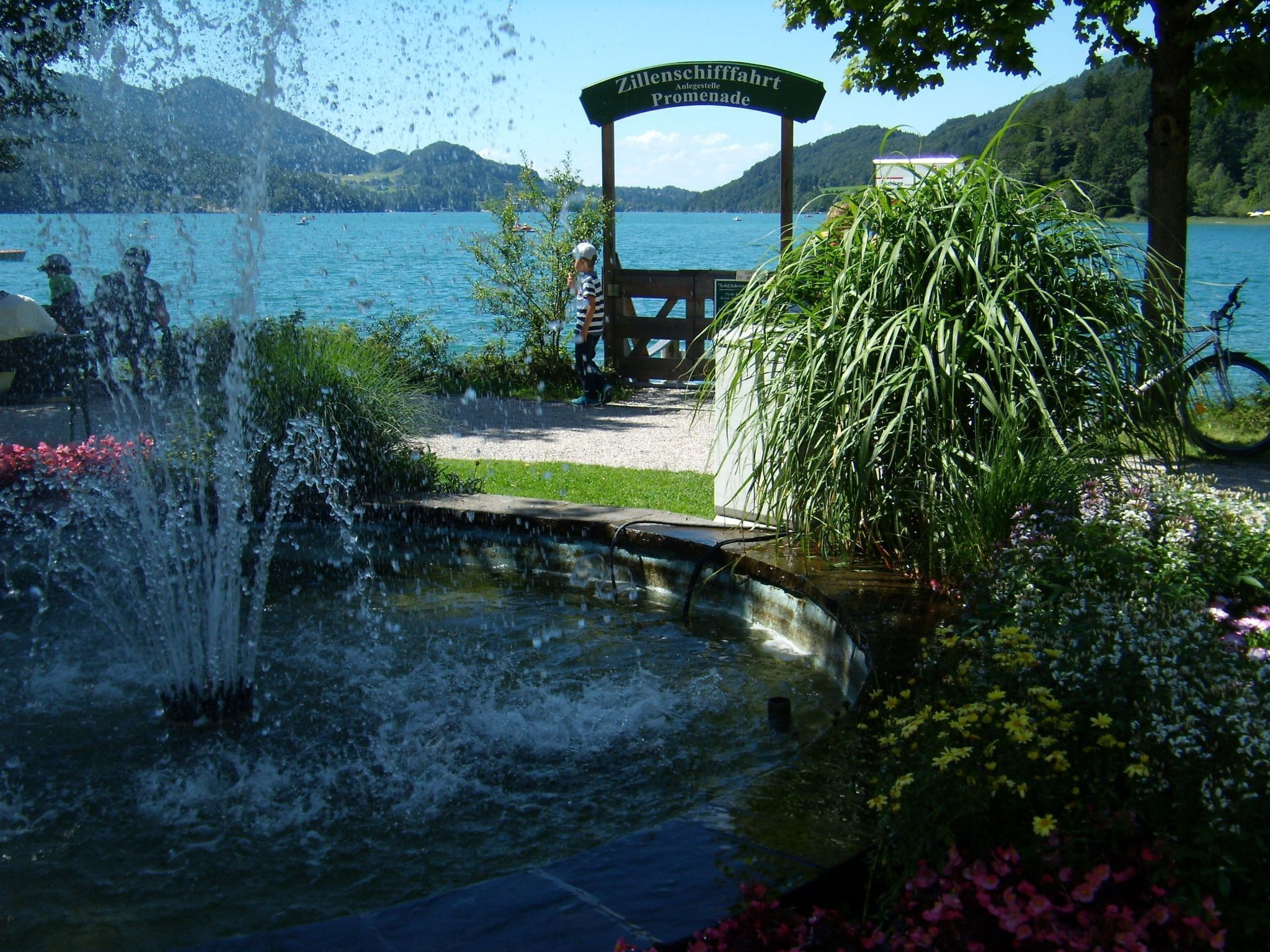 A tranquil garden with a fountain, a wooden bench, and a sign indicating a scenic overlook.