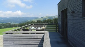 Una terraza de madera con una mesa dispuesta para el té, con vistas a un valle pintoresco.