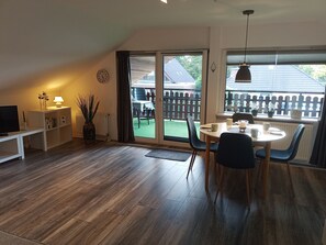 Una habitación acogedora con una mesa de comedor, sillas, un televisor en un mueble bajo y una estantería.