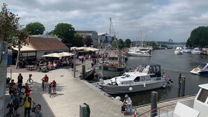 A marina with boats docked, a café area with outdoor seating, and a pedestrian walkway. - Ostsee Perle by Interhome (Niendorf)