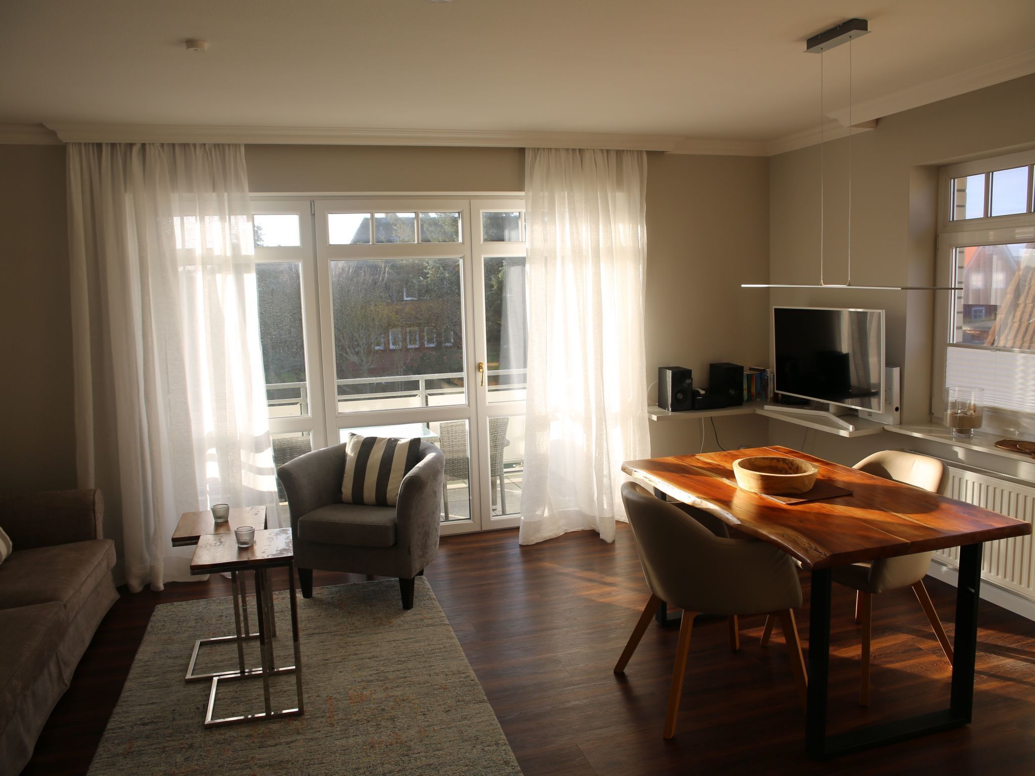 Een moderne woonkamer met een houten eettafel, een bank en een televisie.
