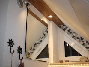 A bathroom with a large mirror, a window with a geometric tile design, and a ceiling with a wooden beam. - Elbkoje Brunsbüttel by Interhome (Brunsbüttel)