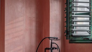 A bathroom with a copper bathtub, a small table with candles, and a chair. - Abode Jaipur (Jaipur)