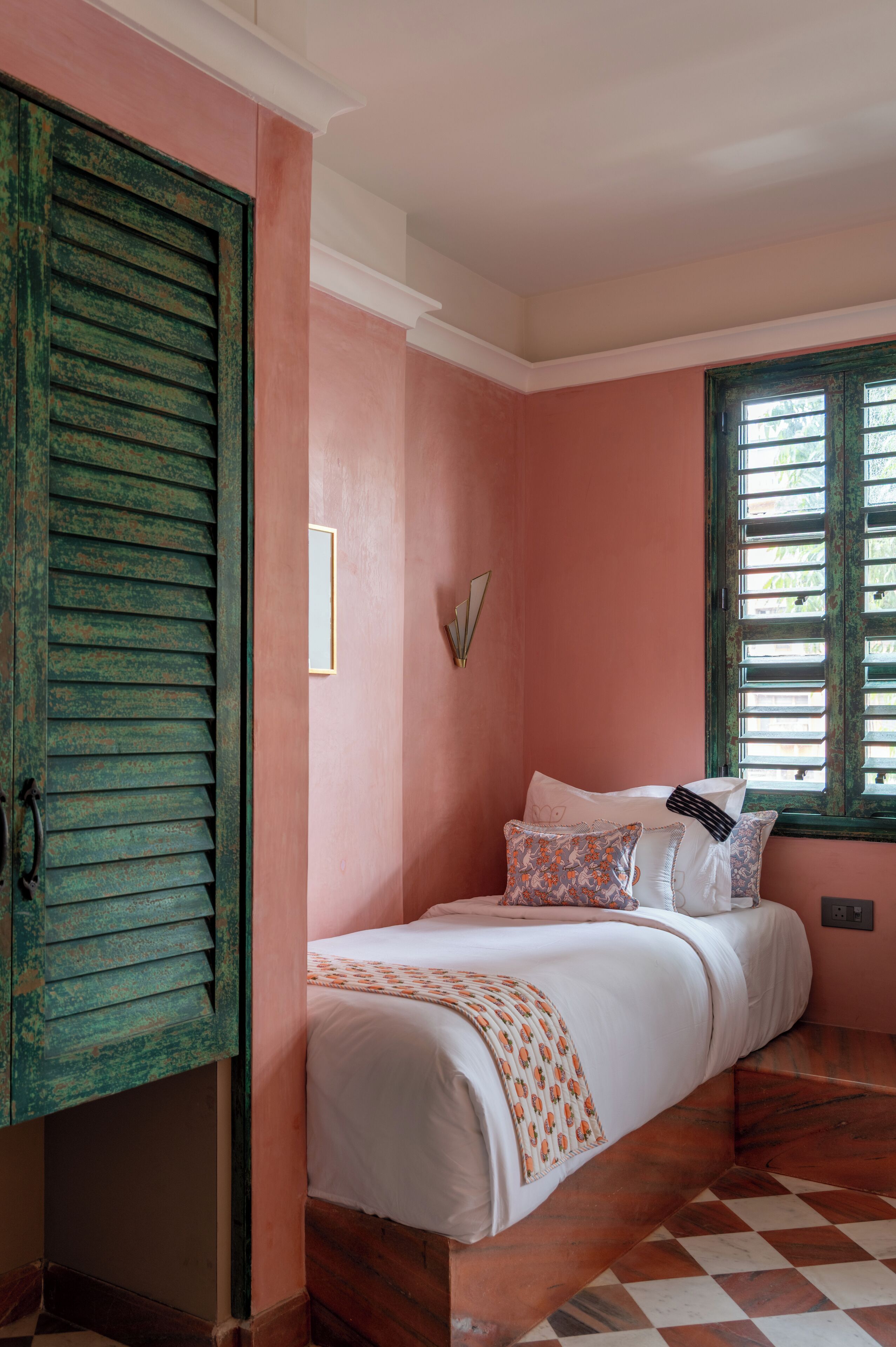 A bedroom with a bed, a window with shutters, and a wooden wardrobe.