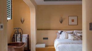 A hotel room with a checkered floor, a bed with white bedding, a bathtub, and a wall-mounted light fixture. - Abode Jaipur (Jaipur)