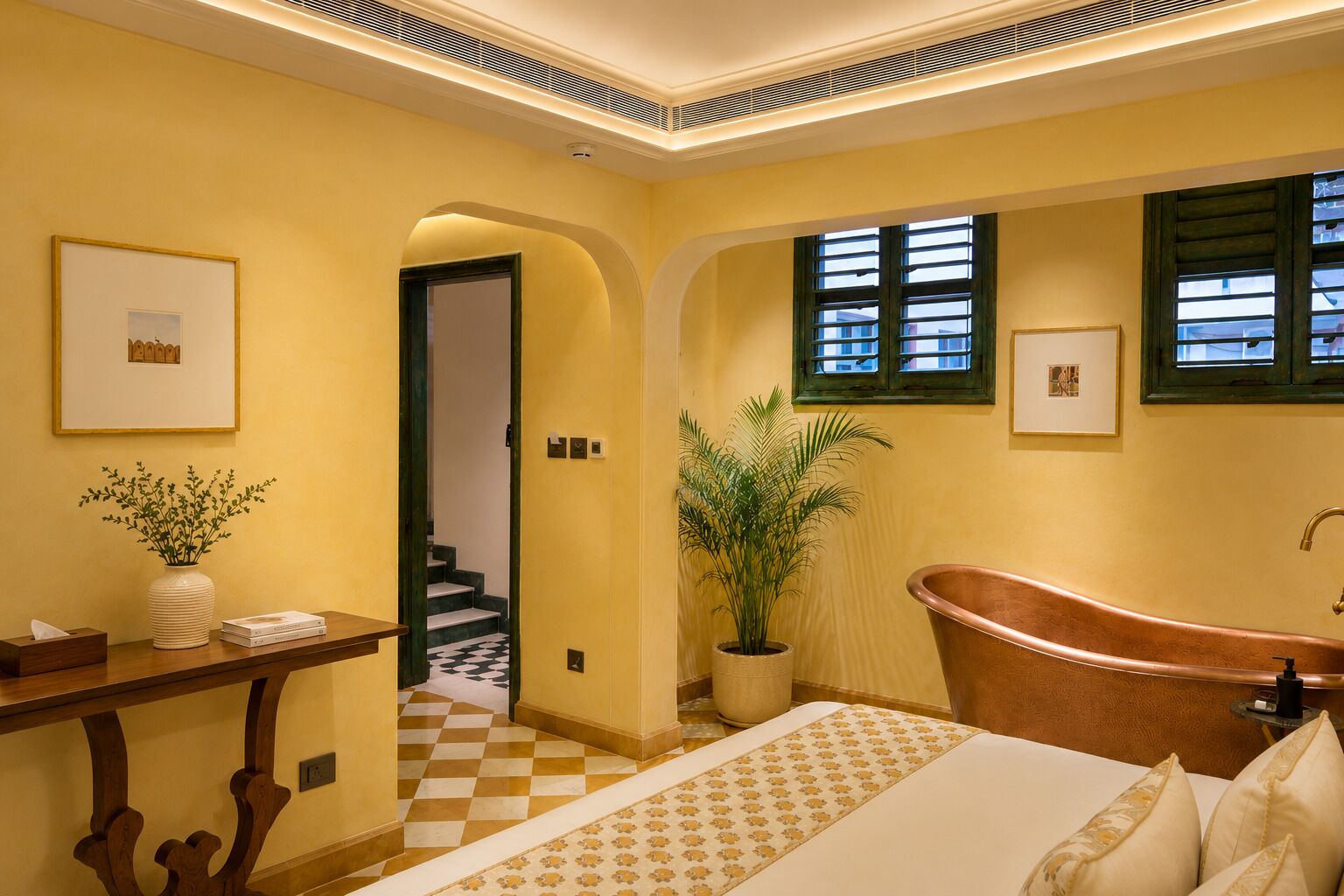 A bathroom with a bathtub, a potted plant, and a framed picture on the wall.
