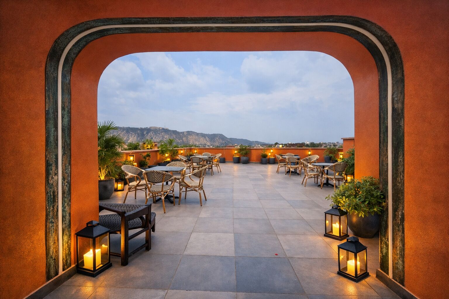 A rooftop terrace with outdoor seating, potted plants, and lanterns.