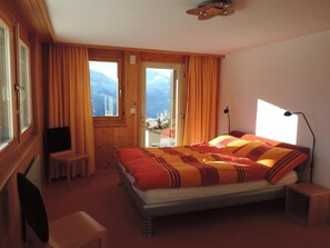 Un dormitorio con cama, televisor, escritorio y silla.