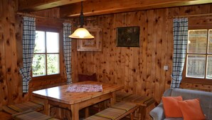 A wooden interior with a dining table, benches, a sofa, and plaid curtains. - Guglhütte by Interhome (Reichenfels)