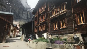 Un pueblo de montaña con edificios de madera, una calle empedrada y un coche estacionado en la entrada.
