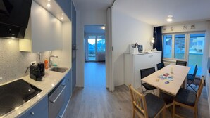 Una cocina moderna con estufa integrada, pileta y alacenas. Cuenta con un comedor con mesa y sillas, y vista al exterior a través de una ventana.