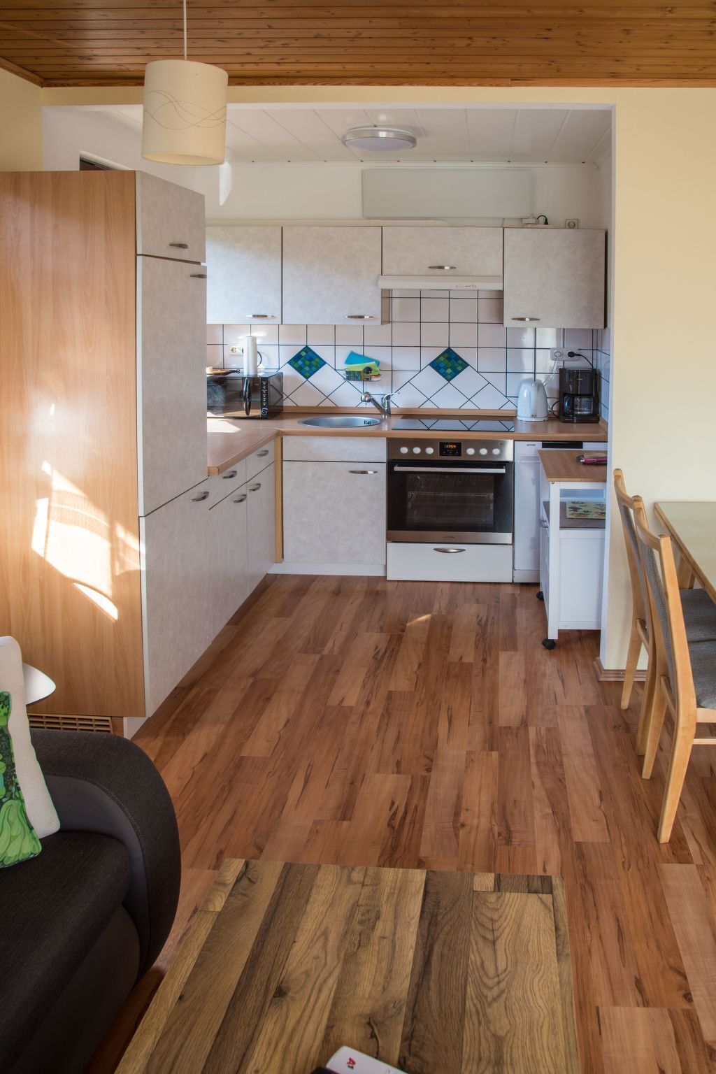 Une cuisine moderne avec des meubles en bois, un four encastré et une machine à café.