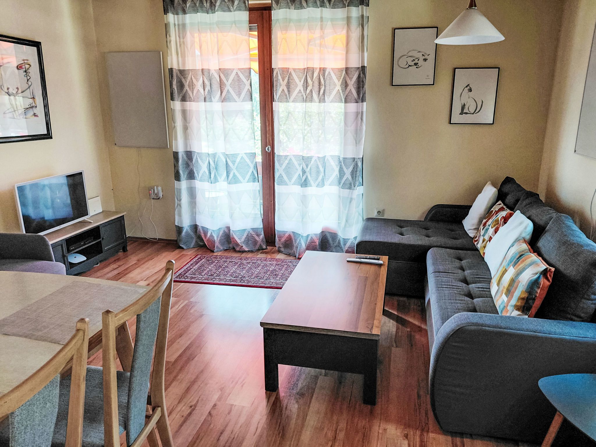 Ein Wohnzimmer mit einer Couch, einem Couchtisch, einem Fernseher und einem Essbereich mit Tisch und Stühlen.