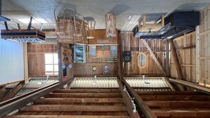 A rustic interior with exposed wooden beams, a central wooden structure, and a metal-framed window. - Sonnenschein1 by Interhome (Eibiswald)