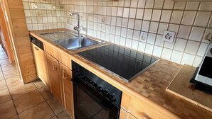 Une cuisine de taille réduite, avec des meubles en bois, une cuisinière noire, un évier et un lave-vaisselle.