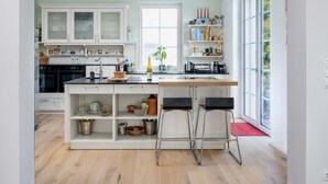 A modern kitchen with white cabinets, a central island, and bar stools.