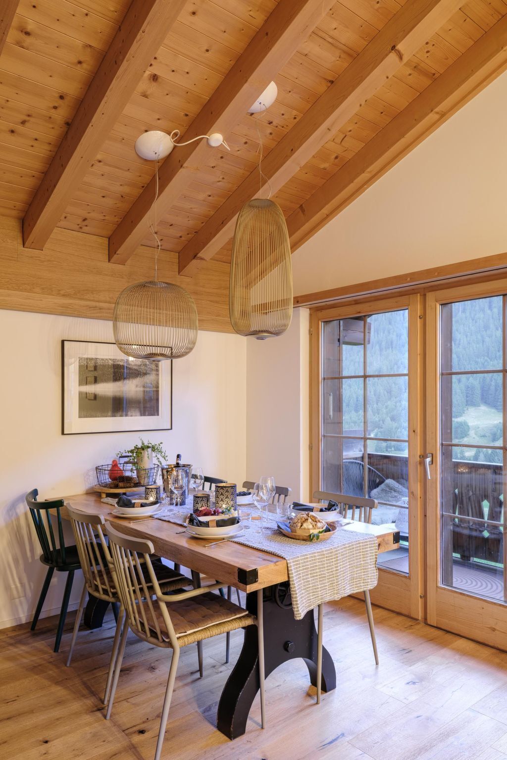 A dining area with a wooden table, chairs, and hanging pendant lights.