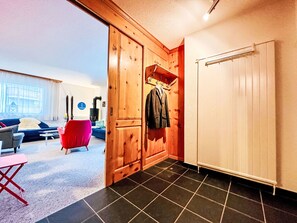 A room with a wooden wardrobe, a radiator, a red chair, and a sofa. - Apartment Cervin by Interhome (Zermatt)