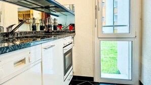 Cuina amb forn de generació pròpia, un rentamiques d'acer inoxidable i una finestra amb vista a una zona verda.