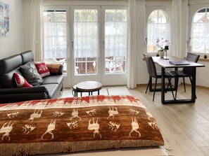 A living room with a sofa, a round coffee table, and a dining area with a table and chairs. - Geräumiges Studio (42 m²) – Matterhorn Panoramab by Interhome (Zermatt)