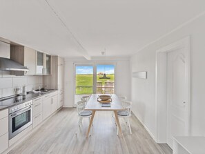 Een koelkast, een oven, een vaatwasser, kookgerei, borden en bestek