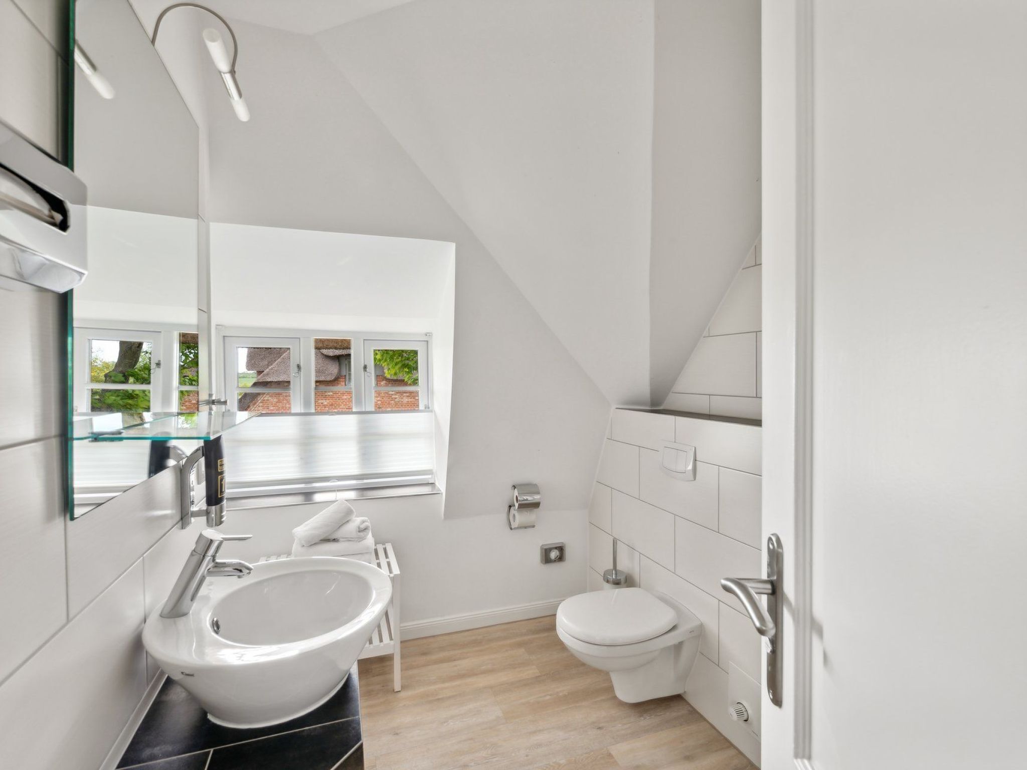Une salle de bain moderne avec un grand miroir, un lavabo blanc et des toilettes.