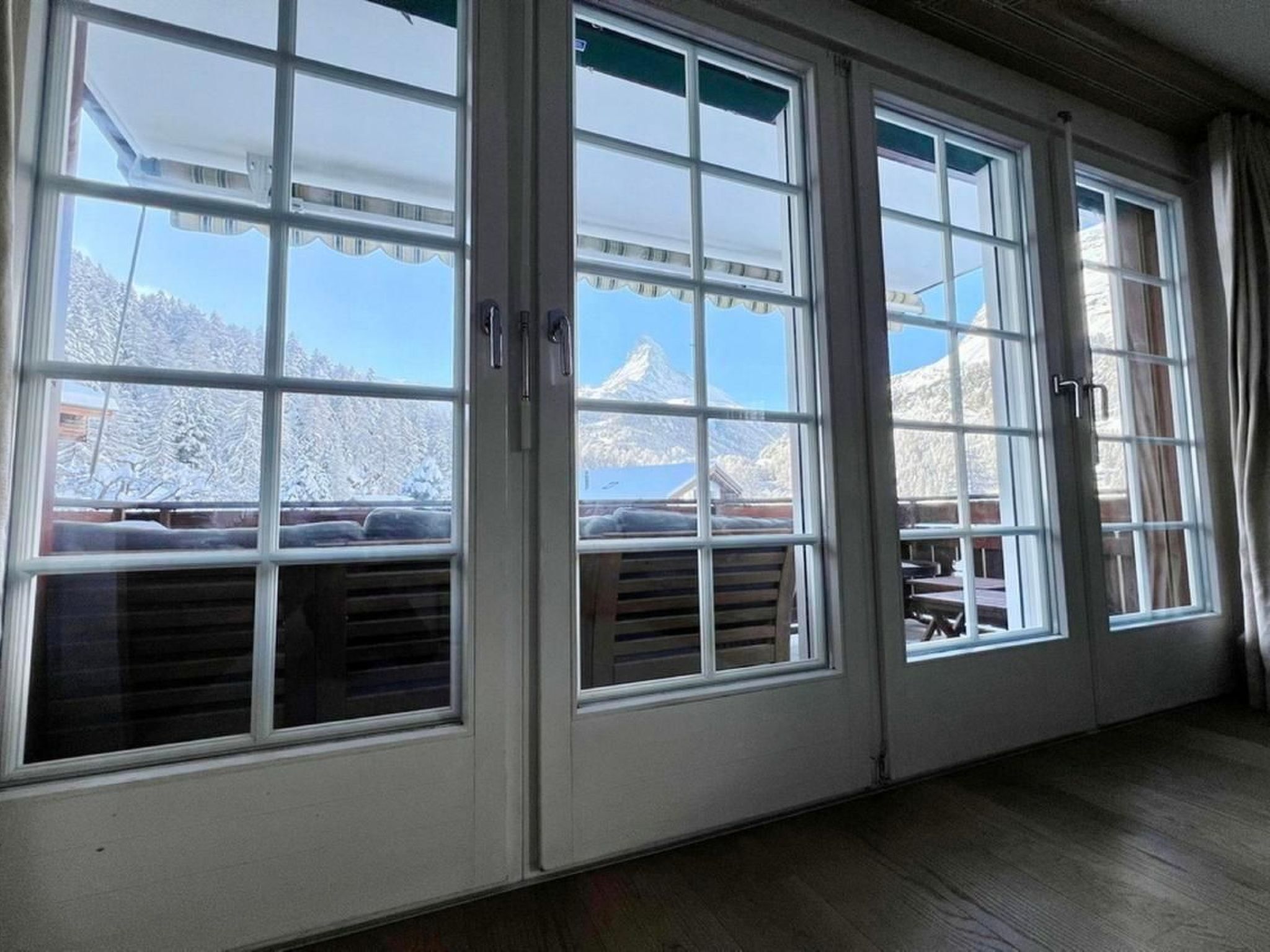 Quarto com grandes janelas oferecendo vista para montanhas cobertas de neve.