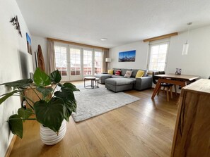 A spacious living room with a grey sofa, a dining table, and a large potted plant. - Apartment mit fantastischem Blick aufs Matterhor by Interhome (Zermatt)