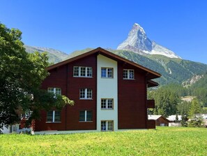 A two-story building with a symmetrical facade, large windows, and a prominent mountain peak in the background. - Apartment mit fantastischem Blick aufs Matterhor by Interhome (Zermatt)