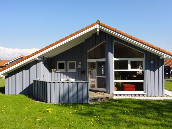 En enplansbyggnad med ett sluttande tak, stora fönster och en liten veranda.