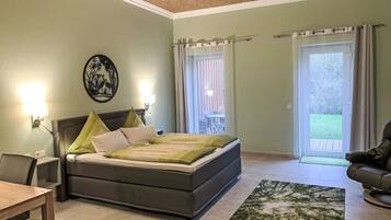 Ein Schlafzimmer mit Bett, Stuhl, Tisch und Blick ins Freie.
