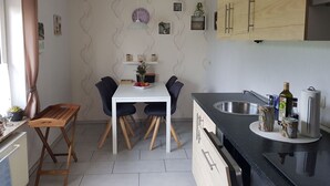 Una cucina compatta con tavolo, sedie e un piano di lavoro nero con lavello.