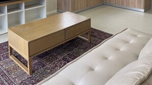 Ein modernes Wohnzimmer mit einem Flachbildfernseher, einem Holztisch und einem weißen Sofa.