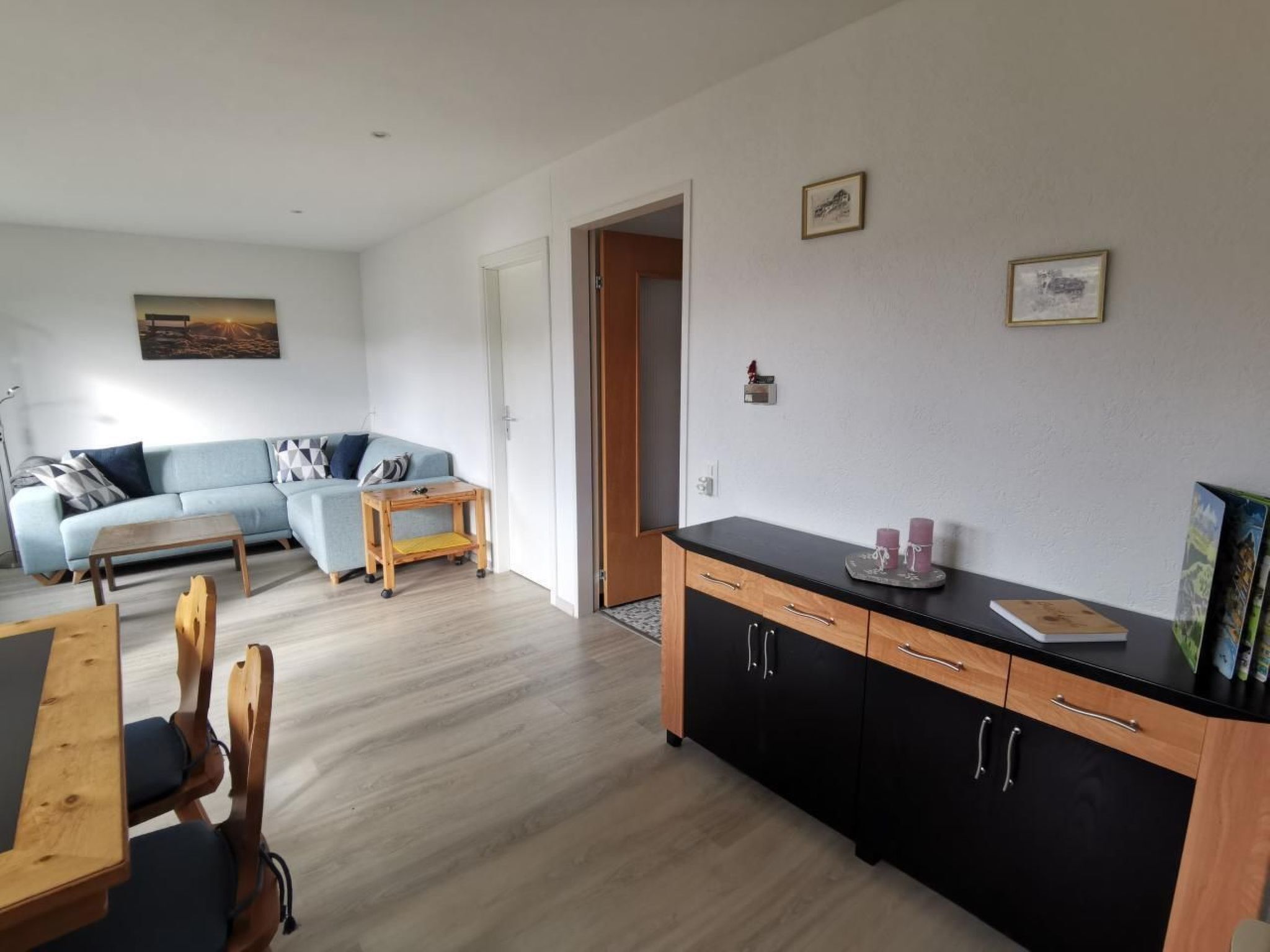 Ein stilvolles Wohnzimmer mit Sofa, Esstisch und Küchenzeile.