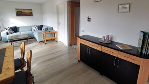 Ein stilvolles Wohnzimmer mit Sofa, Esstisch und Küchenzeile.